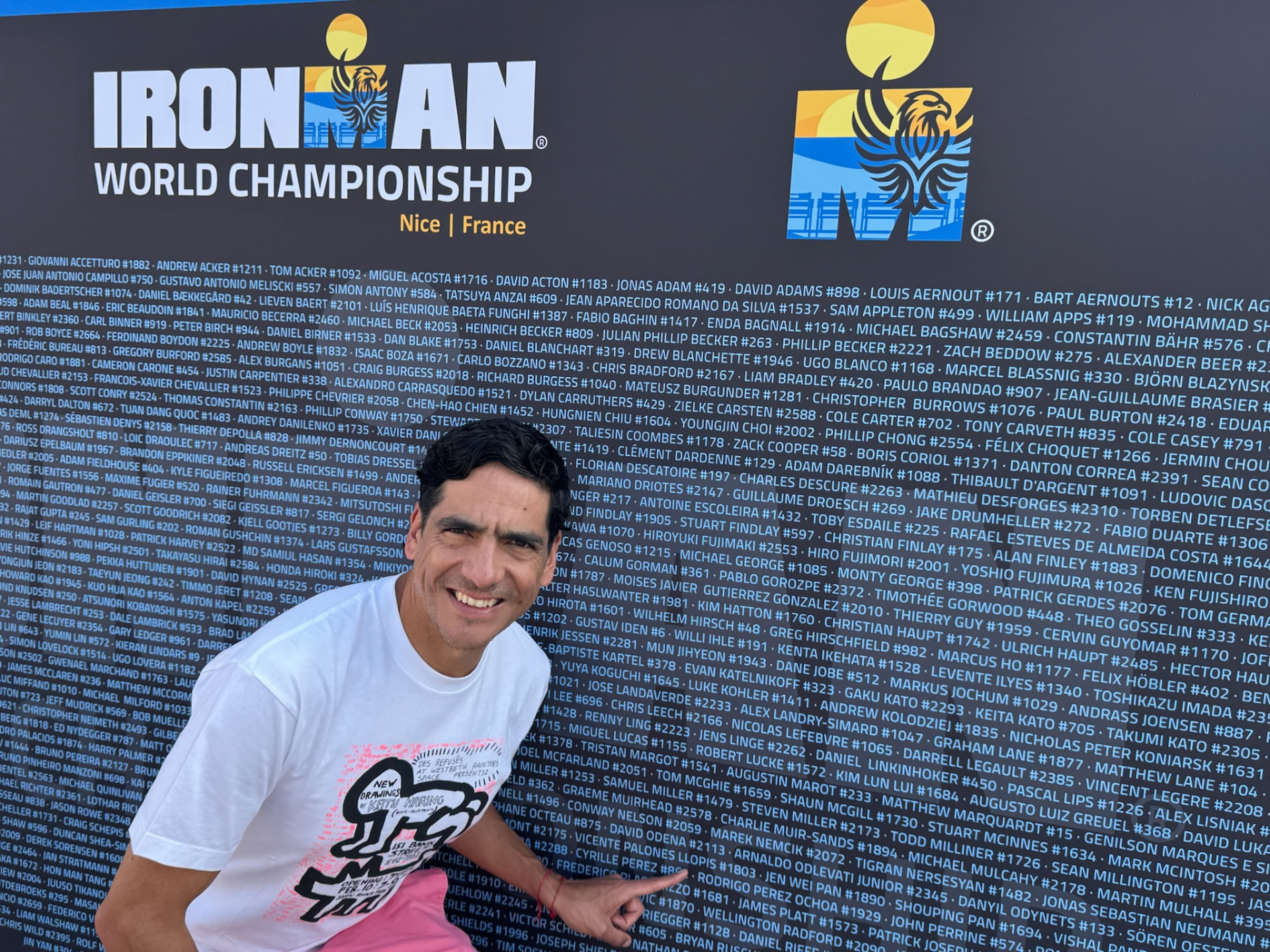 Rodrigo señalando su nombre en el mural de atletas del Ironman World Championship.