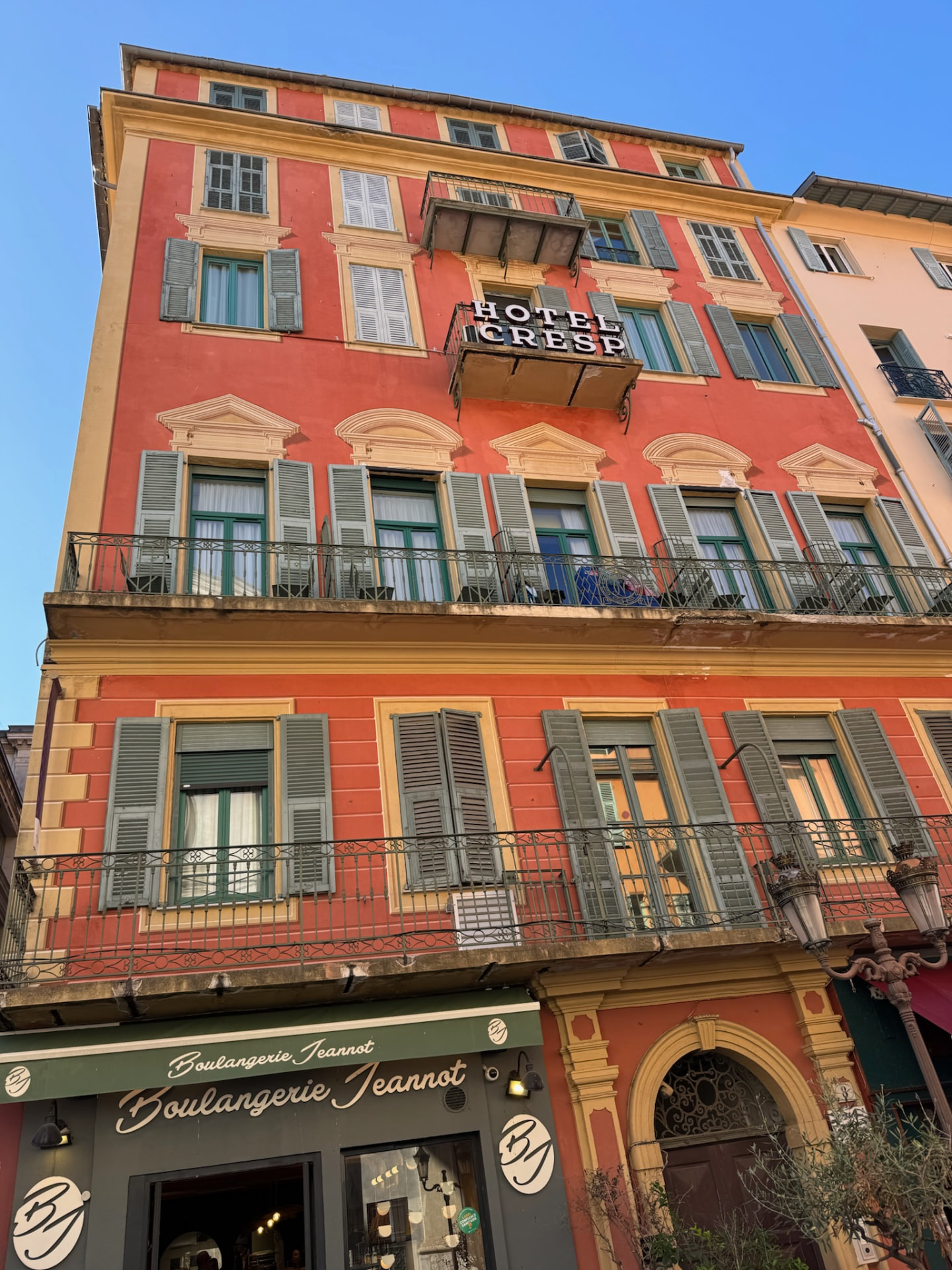 Fachada naranja del Hotel Cresp con sus ventanas trompe-l'œil.